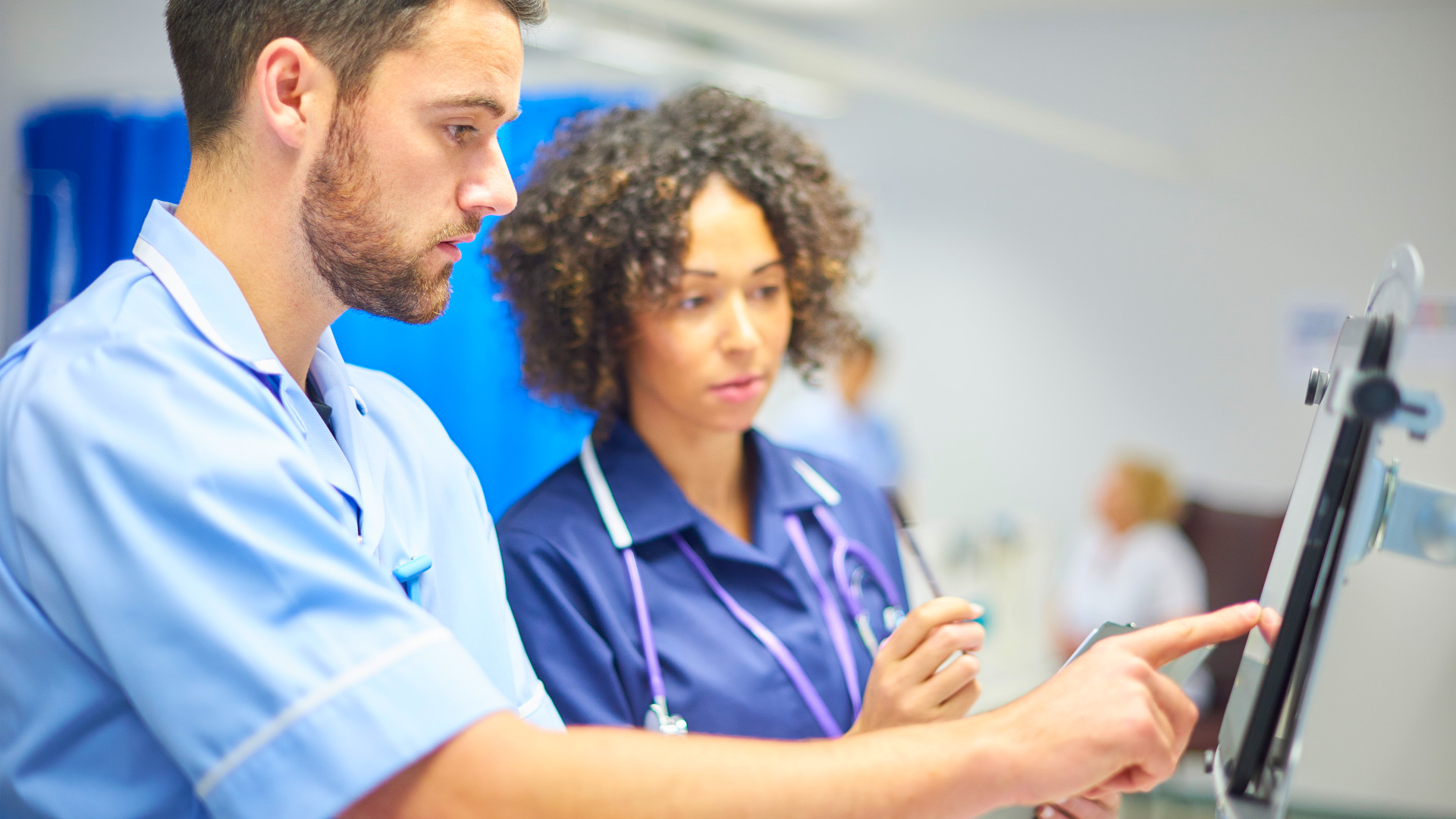 Digitalisierung im Gesundheitswesen: Pflegekraft und Ärztin überprüfen Daten auf einem Tablet im Krankenhaus. 